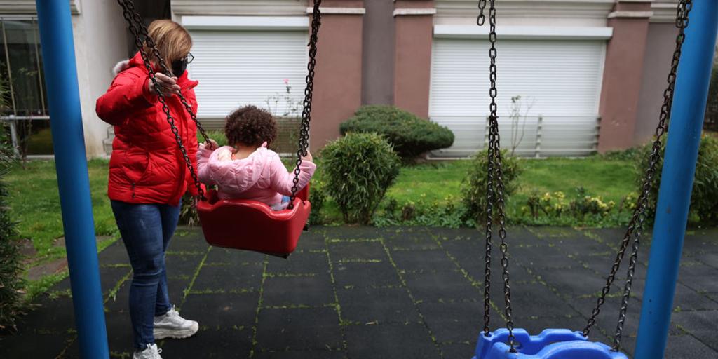 a young girl plays at the park with her mother