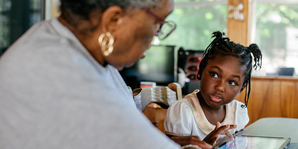 a young girl sits and talks with her grandmother