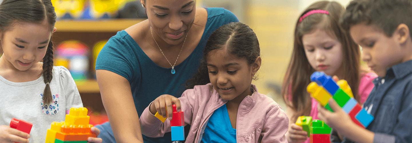 A woman helps several young children in a child care setting