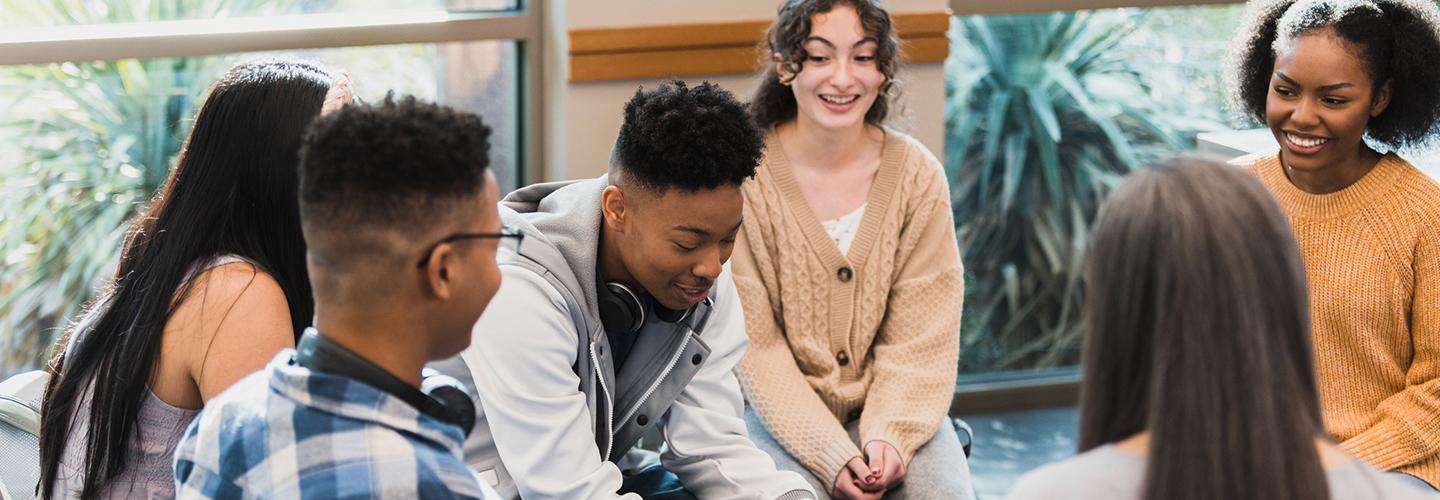 a young man talks in a group of peers