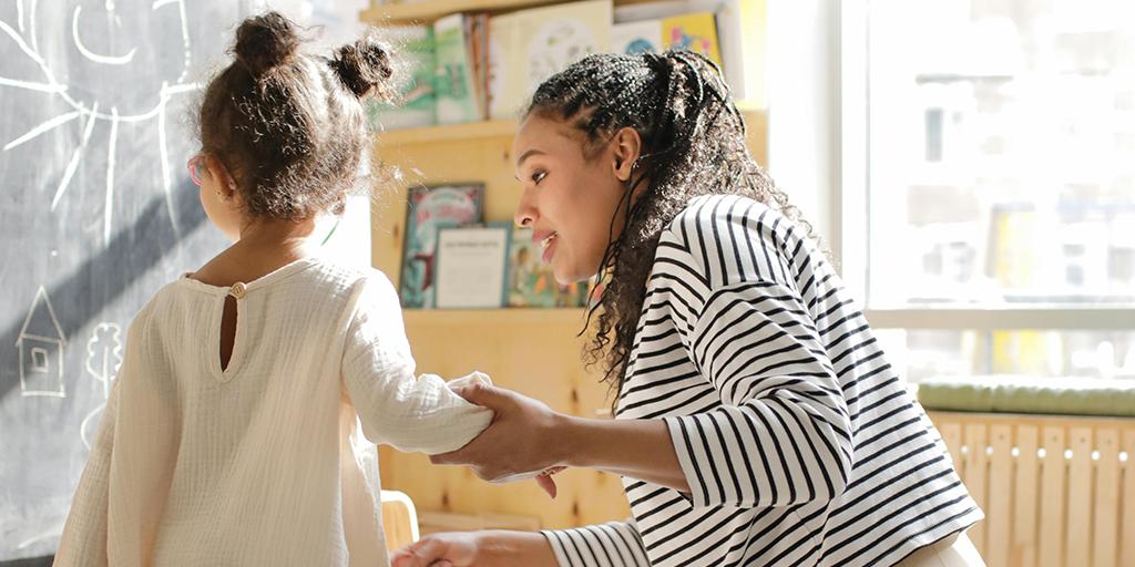 a teacher holds a girl's hand in class